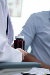  An Asian female doctor is giving medication to a patient who comes to the hospital for urinary tract treatment.