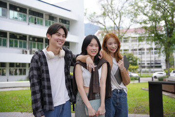 Three cheerful asian students standing together on a campus lawn, enjoying their time at university