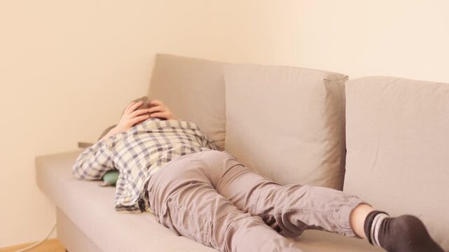 10-year-old boy in frustration, lying on sofa, punching pillows, experiencing teenage angst and tantrums, coping with emotions, angst and frustration, mental health