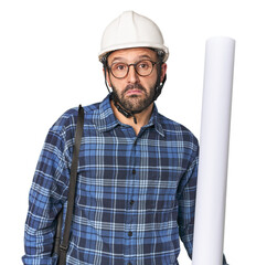 Hispanic male architect with plans shrugs shoulders and open eyes confused.