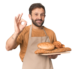 Hispanic male baker with bread tray cheerful and confident showing ok gesture.