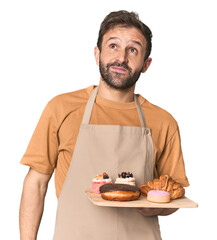 Hispanic male baker with pastries dreaming of achieving goals and purposes