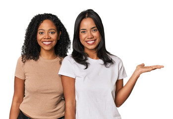 Young Latin friends in studio showing a copy space on a palm and holding another hand on waist.