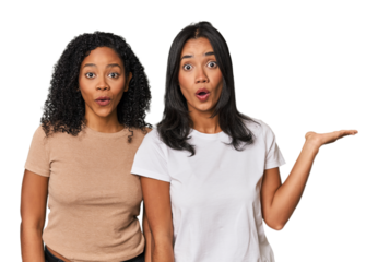 Young Latin friends in studio impressed holding copy space on palm.