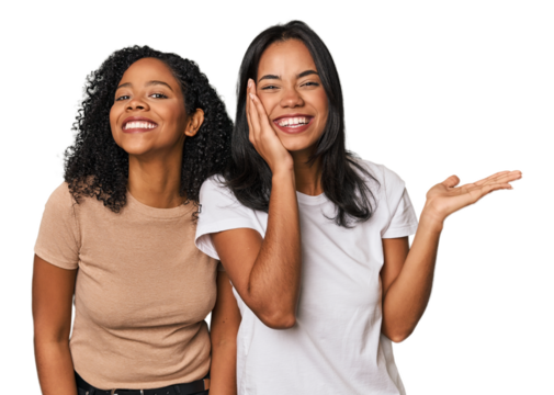 Young Latin friends in studio holds copy space on a palm, keep hand over cheek. Amazed and delighted.