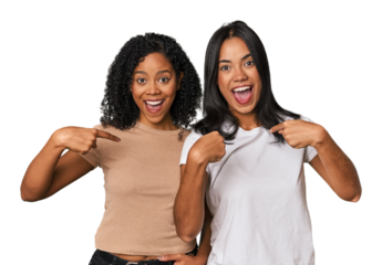 Young Latin friends in studio surprised pointing with finger, smiling broadly.