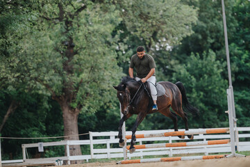 Obraz premium Man riding horse jumps over barrier in outdoor equestrian arena. Equestrian sport activity showcasing skill and training.