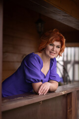 Portrait of a beautiful young red-haired girl in a purple dress.