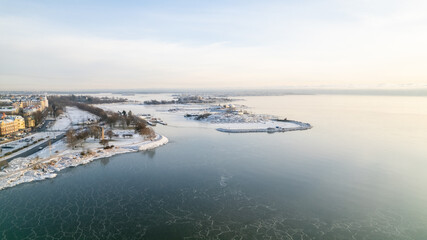Fototapeta premium drone aerial view on Snowy cold winter day in Helsinki Finland on a sunny day in the sea side, sea covered with ice