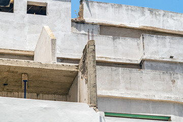 A multi-storey building under construction with a heterogeneous layout, balconies and ledges along edges. Stage of construction of load-bearing walls. cracks in masonry sharp evaporation of moisture