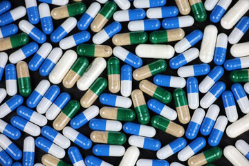 Blue white and green gray pills, variation of scattered medication in capsules. Horizontal background for pharmacy, antibiotics, vitamins