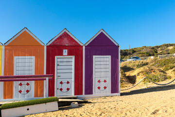 Cabañas de playa en colores amarillo, rojo y purpura para cambiarse de ropa en la playa de...