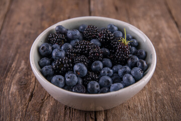 Ripe black blackberries and blue blueberries on a wooden table