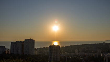 Panoramic top view of the evening city of Sochi with a beautiful sunset and buildings blurred in the haze among the trees