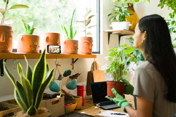 Latin woman shooting a video tutorial in her plant store with her smartphone