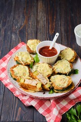 Zucchini stuffed with minced chicken and baked with cheese and herbs on a ceramic plate on a dark wooden background. Zucchini recipes.