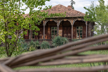 Old Georgian traditional rural wooden house with tiled roof surrounded by trees, Tbilisi, Georgia