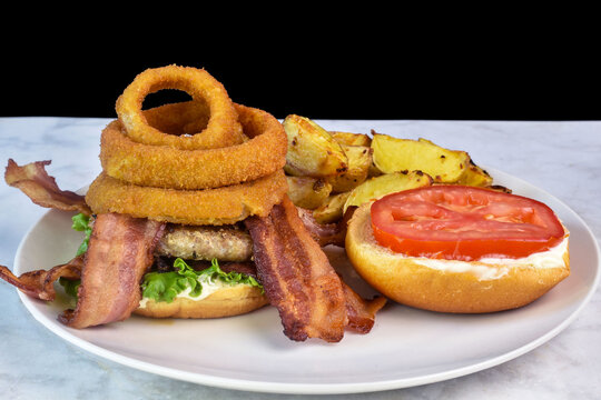 bacon burger top with onion rings  served with potato wedges