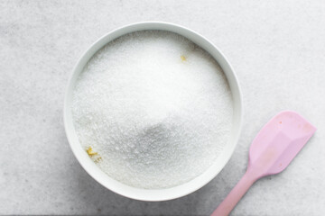 Overhead view of white sugar in a white bowl, top view of granulated sugar in a bowl