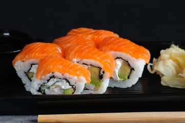 Close-up of salmon rolls in an open black plastic container. Selective focus