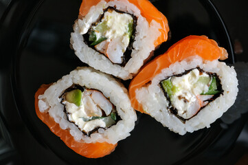Top view of sushi rolls on black plate with cream cheese cucumber and avocado. Close up