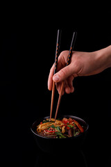 Stir fry noodles with vegetables and shrimps in black bowl. Slate background. Top view. Copy space.