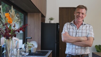 Happy old grandfather confidently standing pose while look at camera for good event or anniversary in kitchen. Cheerful senior enjoy retirement life with beautiful kitchenware and house. Divergence.