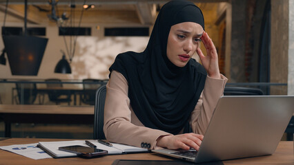 Displeased sad worker muslim islamic businesswoman in hijab upset online project mistake Arabian man businessman boss coach come help trainee solve problem excited happy woman working laptop in office