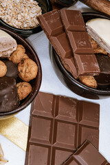 Chocolate chip cookies, chocolate bar and white chocolate, small bowl oatmeal and nuts. International Chocolate Day.