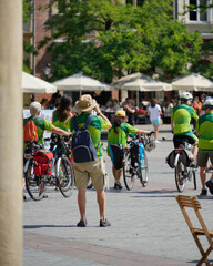 A tech-savvy man takes photos of cyclists gathered in a town square, capturing the vibrant energy of modern life. This dynamic scene showcases the intersection of technology and urban living