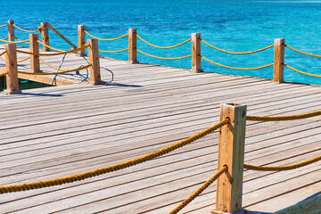 Fototapeta premium Marine wooden dock with yellow ropes and blue clear water