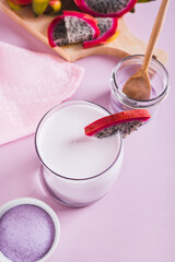 Pink matcha latte in a glass and dragon fruit powder in a bowl on the table vertical view