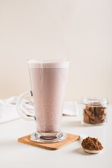 Healthy chocolate protein drink in a glass and powder in a jar on the table vertical view