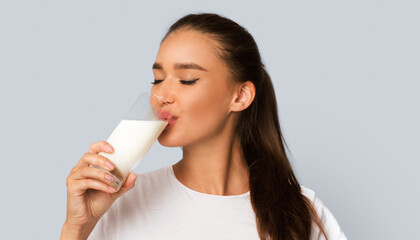 Dairy Products. Young Woman Drinking Milk From Glass Standing Over White Studio Background. Isolated