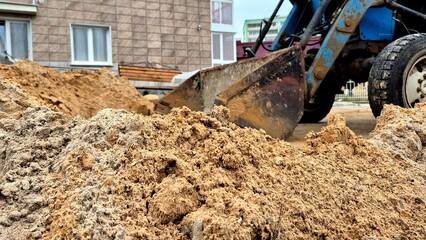 Fototapeta premium Construction Workers Using Heavy Machinery to Move Sand at Urban Building Site in Daylight