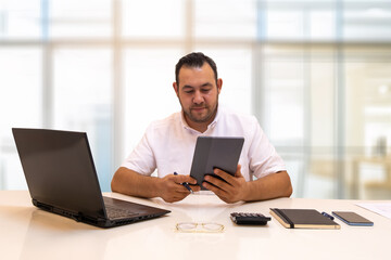 The boss looks happy while doing various reviews on his tablet. An example of busy work schedule and technological innovation. Business life.