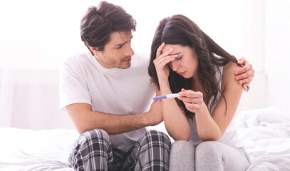 Couple dreaming to be parents. Upset man comforting his depressed wife with negative pregnancy...