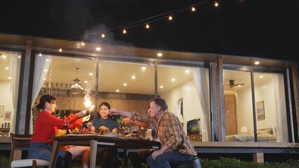 Happy family holding glowed sparkler in holiday celebration party at night. Lovely member enjoy playing spark toy together. Outdoor activity to cross generation gap strengthen family bond. Divergence.