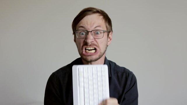 Angry and frustrated man office worker screaming and eating keyboard
