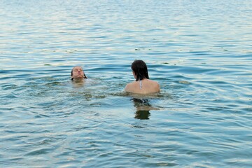 Two girls swim in the river in the evening in turquoise water