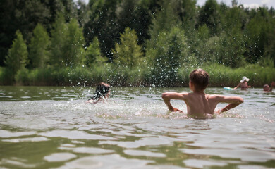 Fototapeta premium Children swim and play in the lake