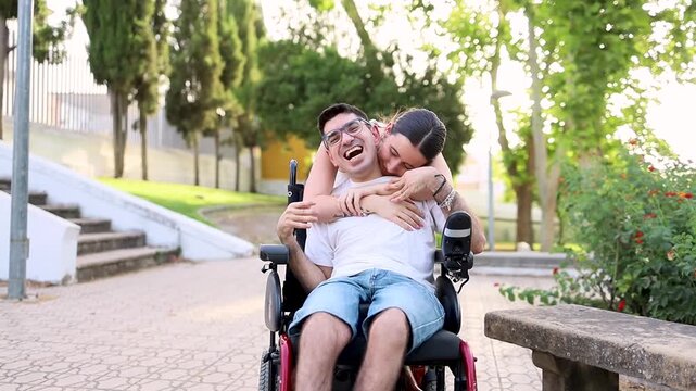 A young girl cares for an adult man with cerebral palsy in a park at sunset.Young woman walks disabled man in an outdoor park.Concept of people with dependence due to cerebral palsy.