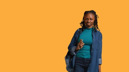 Anxious student at school thinking of raising arm to answer question but unsure of herself, studio background. Teenager lacking confidence needed to volunteer saying explanation to question, camera B