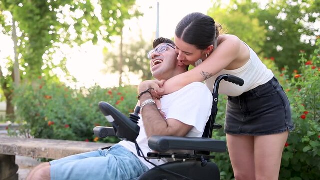 A young girl cares for an adult man with cerebral palsy in a park at sunset.A young woman hugs a disabled man happily from behind on the street.Concept of people with dependence due to cerebral palsy.