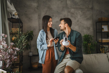 Adult couple connect cctv surveillance camera with mobile phone at home