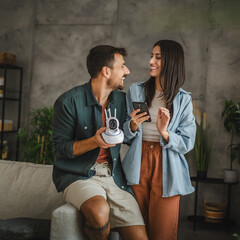 Adult couple connect cctv surveillance camera with mobile phone at home