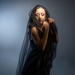 A Gothic bride, a mysterious Halloween image, a Gothic gloomy aesthetic. An elegant young woman in a black dress and with a veil on her face