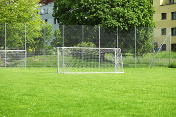 Fototapeta premium White football goal. Empty goal against summer green football field