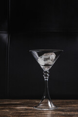 Martini glass with two icecubes on leather dark background