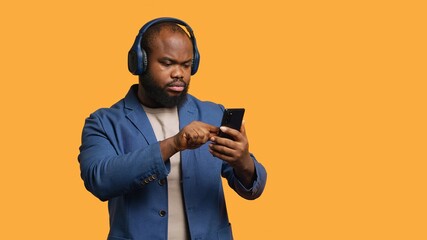 Smiling african american man listening to music on bluetooth headphones connected to smartphone....